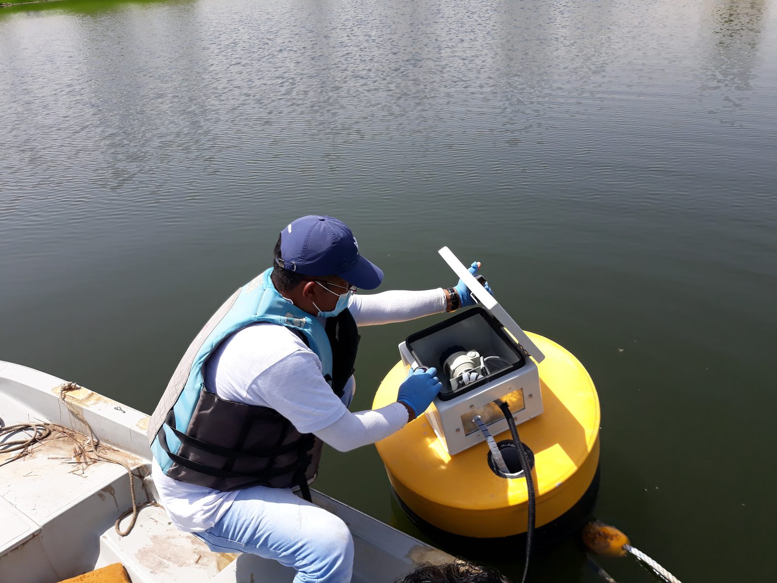 Alpha technician servicing the control unit on a floating aeration buoy in a Dubai lake